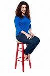 Long Curly Haired Lady Seated On Red Stool Stock Photo