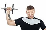 Male Instructor Posing With Raised Dumbbell Stock Photo