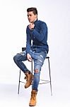 Male Model In Denim Jeans Sitting On A Chair . Studio Shoot Stock Photo