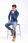 Male Model In Denim Jeans Sitting On A Chair . Studio Shoot Stock Photo