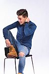 Male Model In Denim Jeans Sitting On A Chair . Studio Shoot Stock Photo