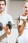 Man And Woman Lifting Dumbbell In Gym Stock Photo