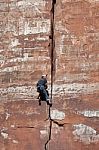 Man Climbing Sheer Rock Face In Zion National Park Stock Photo