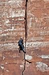 Man Climbing Sheer Rock Face In Zion National Park Stock Photo