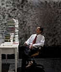 Man Looking To Big Stack Of Book On Working Table Stock Photo