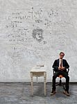 Man Sitting On Desk And Physic Formula On Wall Stock Photo
