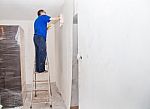 Man Smoothing The Wallpaper On The Wall Stock Photo