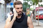 Man With A Beard Talking With Your Smart Phone On The Street Stock Photo