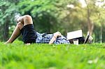 Mature Man Sleeping On Green Grass In City Park  With A Book Cov Stock Photo