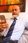 Middle-aged Businessman Listening On Smartphone At Home Stock Photo