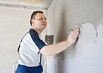 Middle-aged Man Worker Putting Plaster On The Wall Stock Photo