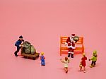 Miniature Santa Claus, A Man With Trolly And Children On Pink Ba Stock Photo