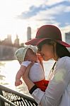 Mom Is Kissing Her Baby With The City In The Background Stock Photo