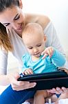 Mother And Baby Girl Using Digital Tablet At Home Stock Photo