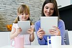 Mother And Daughter Using A Digital Tablet In Kitchen Stock Photo