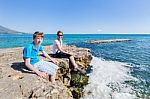 Mother And Son As Tourists Sitting On Rock At Blue Sea Stock Photo