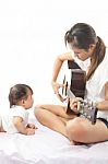Mother Is Playing A Guitar For Her Baby Stock Photo