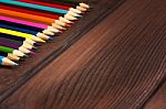 Multicolored Pencils On A Background Of Dark Wood Tables Stock Photo