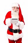 Old Man In Santa Dress Using Tablet Pc Stock Photo