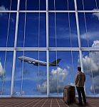 Passenger Standing With Big Suitcase In Airport And Looking To A Stock Photo