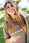 Portrait Of Beautiful Girl Listening To Music With Digital Table Stock Photo