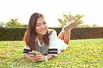 Portrait Of Beautiful Young Woman Lying On Green Grass Field And Stock Photo