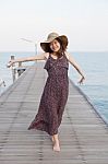 Portrait Of Beautiful Young Woman Wearing Wide Straw Hat And Long Dress Standing With Happiness Emotion On Piers At Sea Beach Stock Photo