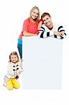 Portrait Of Happy Family Presenting Blank Whiteboard Stock Photo