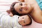 Portrait Of Happy Young Attractive Hispanic Mother Lying With He Stock Photo