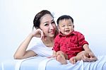 Portrait Of Laughing Asian Mother And Sitting Baby On Bench Stock Photo