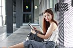 Portrait Of Thai Adult Beautiful Girl Using Her Tablet And Smile In University Stock Photo