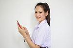 Portrait Of Thai High School Student Uniform Teen Beautiful Girl Using Her Phone And Smile Stock Photo