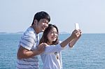 Portrait Of Young Man And Woman Selfie ,self Portrait By Mobile Phone In Relaxing Emotion Sea Beach Destination Use For People In Modern Life Style Stock Photo