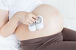 Pregnant Belly With A Pair Of White Shoes Stock Photo