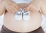 Pregnant Belly With A Pair Of White Shoes Stock Photo