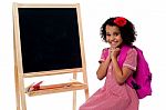 Pretty Girl Sitting Near Blank Chalk Board Stock Photo