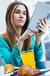 Pretty Woman Using Tablet While Having Breakfast In Coffee Shop Stock Photo