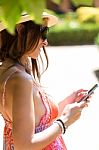 Pretty Young Girl Texting On Mobile Phone In The Garden Stock Photo