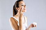 Pretty Young Woman Applying Body Cream. Isolated On Gray Backgro Stock Photo