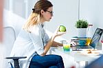 Pretty Young Woman Eating An Apple And Working At Home Stock Photo