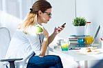 Pretty Young Woman Eating An Apple And Working At Home Stock Photo