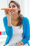 Pretty Young Woman Having Fun With A Carrot In The Kitchen Stock Photo