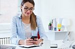 Pretty Young Woman Using Her Mobile Phone In The Office Stock Photo