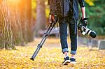 Professional Photographer With Camera And Tripod In Autumn Stock Photo