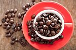Red Coffee Cup With Coffee Beans On Wooden Table Stock Photo