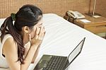 Sad Young Asian Woman Working With Laptop In Bedroom Stock Photo