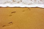 Sea Wave With Foam And Human Footprints On Sand Stock Photo