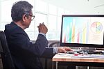 Senior Business Man Working On Office Table With Computer And Business Graph Report , Stock Photo