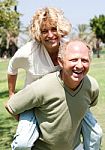 Senior Man Giving Piggy Ride To Her Wife Stock Photo