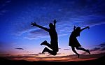 Silhouettes Of Couple Jumping Stock Photo